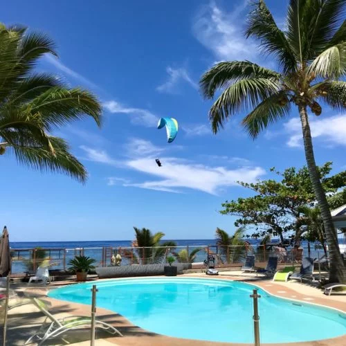 Gleitschirmreise La Reunion Schirm zwischen Palmen und Pool im Landeanflug